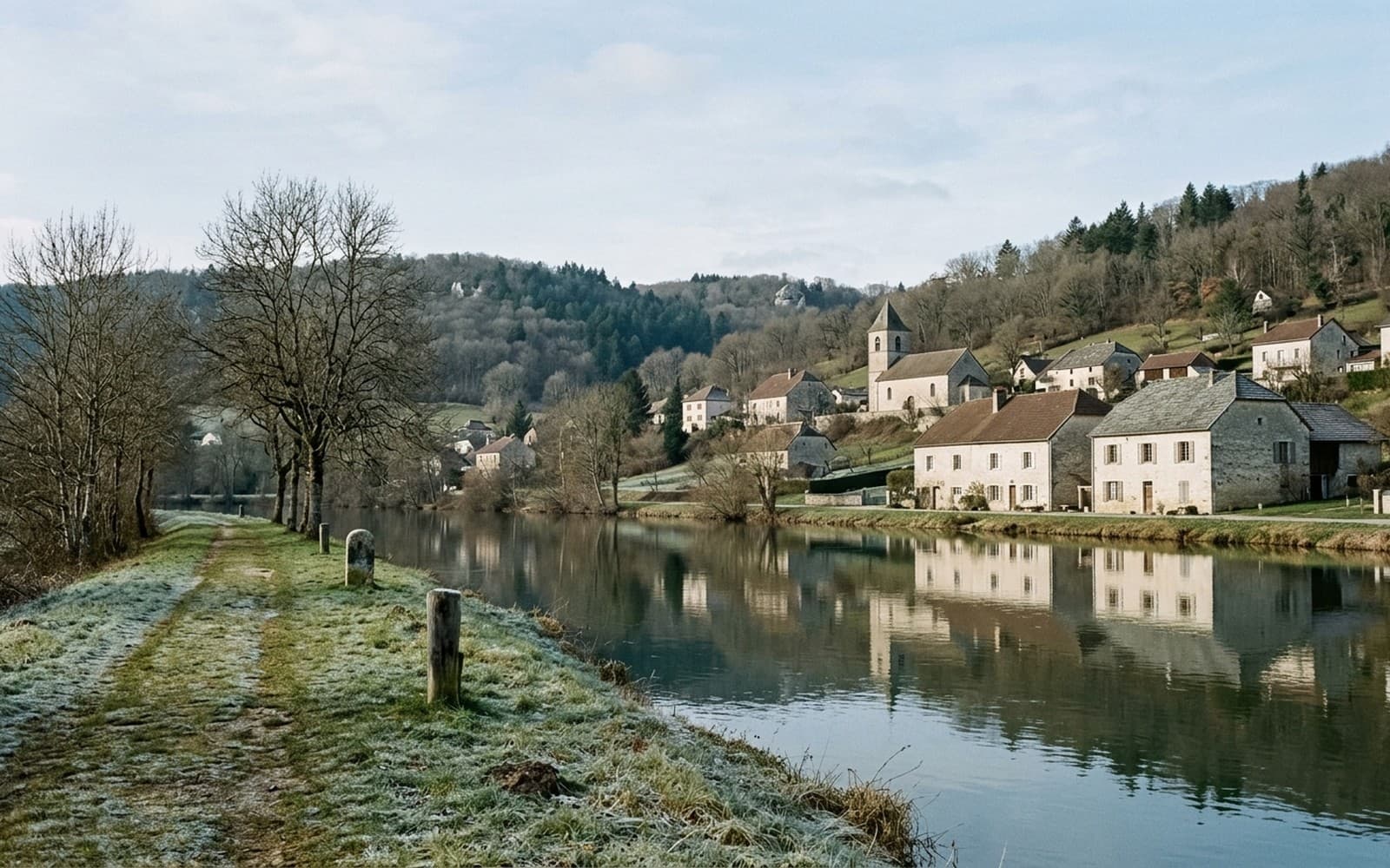 Village de pierre étagé au-dessus d’une rivière, falaises calcaires et versants boisés en surplomb