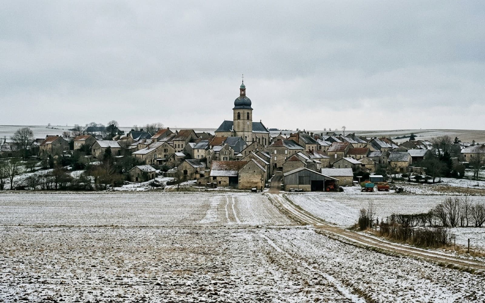 Village groupé autour de son clocher à bulbe, entouré de champs enneigés