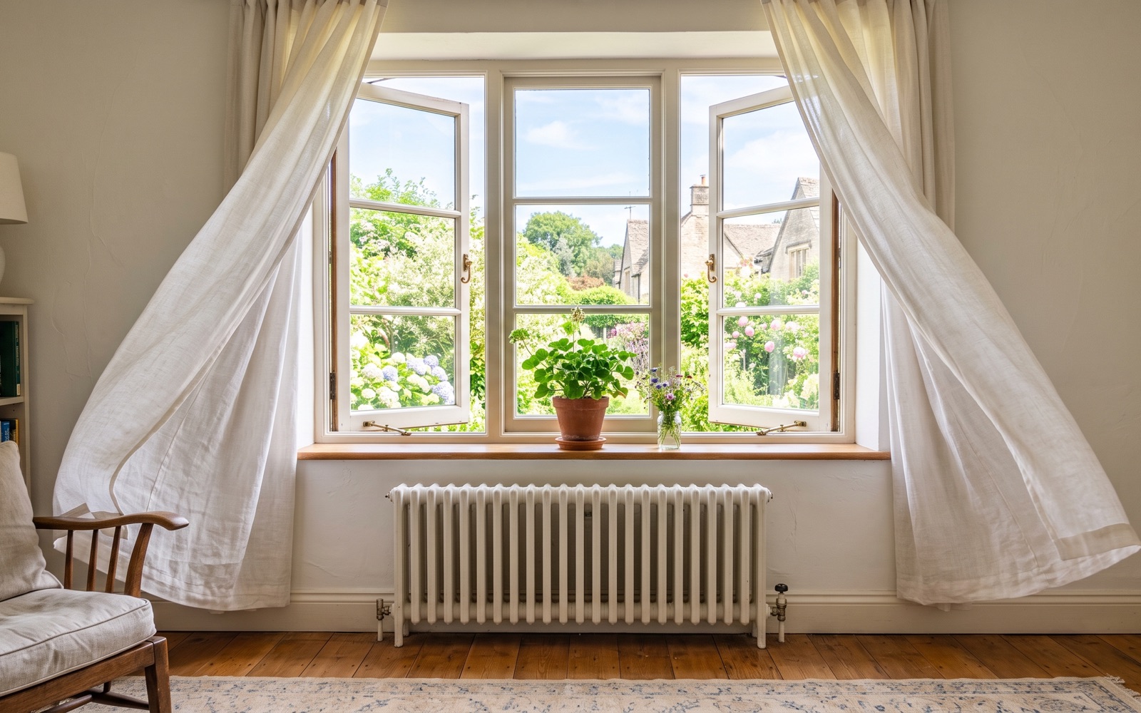 Fenêtre ouverte en grand sur une pièce lumineuse avec un radiateur blanc, rideaux légers soulevés par l'air